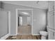Bright bathroom with wood-look flooring, shower, and commode adjacent to doorway with view into another room at 2305 S Rybolt Ave, Indianapolis, IN 46241