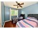 Bedroom featuring blue walls, hardwood floors, a window, and two beds with a ceiling fan above at 2700 Yellowwood Ct, Columbus, IN 47203