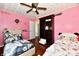 Bright pink bedroom featuring a ceiling fan, wood floors, and two decorated beds at 2700 Yellowwood Ct, Columbus, IN 47203