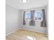 An empty bedroom featuring three windows dressed with gray curtains, light gray walls, and light wood flooring at 3109 Welch Dr, Indianapolis, IN 46224