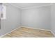 An empty bedroom featuring a window dressed with a gray curtain, light gray walls, and light wood flooring at 3109 Welch Dr, Indianapolis, IN 46224