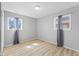 An empty bedroom featuring two windows dressed with gray curtains, light gray walls, and light wood flooring at 3109 Welch Dr, Indianapolis, IN 46224