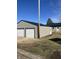 Property view featuring a large two car garage with metal siding, a house with metal roof, and a small patch of grass at 354 Bloomingdale Rd, Montezuma, IN 47862