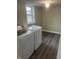 This laundry room features a modern washer and dryer, a window for natural light, and stylish dark wood-look flooring at 354 Bloomingdale Rd, Montezuma, IN 47862