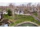 An aerial view shows a modern home with a pond and landscaping, nestled among mature trees and neighboring houses at 395 Breakwater Dr, Fishers, IN 46037