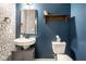 Stylish half bathroom with blue walls and decorated with a shelf, mirror, and sink at 401 Thomas Point Dr, Fortville, IN 46040