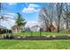 Landscaped backyard with a well-manicured lawn, decorative garden features, and charming outbuildings in the background at 450 W Ash St, Zionsville, IN 46077