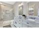 Bright bathroom with a marble vanity, dual sinks, glass shower, and grey flooring at 450 W Ash St, Zionsville, IN 46077