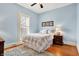 Charming bedroom with light blue walls, ceiling fan, hardwood floors, and bright window at 450 W Ash St, Zionsville, IN 46077