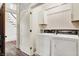 Laundry room with white washer and dryer, patterned wallpaper, and open stairway at 450 W Ash St, Zionsville, IN 46077
