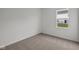 This carpeted bedroom features white walls and a window overlooking the backyard at 5138 Modernist Blvd, Indianapolis, IN 46237