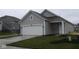Charming gray home featuring a white garage door and front door, complemented by fresh landscaping at 5138 Modernist Blvd, Indianapolis, IN 46237