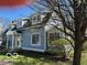 Charming blue two-story home with a well-manicured lawn and blooming tree at 590 W Cedar St, Zionsville, IN 46077