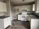 View of kitchen with white appliances, damaged cabinets, and water damaged floor at 6009 Tammin Dr, Indianapolis, IN 46254