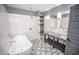 Bright bathroom boasts double vanity, tub, shower, geometric tile floors, and shelving at 615 E Morris St, Indianapolis, IN 46203