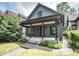 Charming home featuring a covered porch, gray siding, a red door, and lush landscaping at 615 E Morris St, Indianapolis, IN 46203