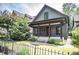 Charming home featuring a covered porch, gray siding, a red door, and lush landscaping at 615 E Morris St, Indianapolis, IN 46203