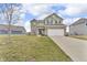 Inviting two-story home featuring a two-car garage, green siding and brick accents at 6180 N Rosewood Dr, McCordsville, IN 46055