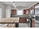 Well-lit kitchen with stainless steel appliances, brown cabinetry, and wood table at 6180 N Rosewood Dr, McCordsville, IN 46055