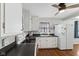 Bright kitchen featuring white cabinetry, dark countertops, stainless steel sink, and a ceiling fan at 633 Fletcher Ln, Beech Grove, IN 46107