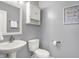 Well-lit half-bathroom with pedestal sink, toilet, and cabinet for storage at 6545 Briarwood Pl, Zionsville, IN 46077