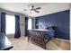 Bedroom with blue accent wall, ceiling fan, and two large windows with dark curtains at 6545 Briarwood Pl, Zionsville, IN 46077