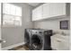 Functional laundry room equipped with modern washer/dryer units and a utility sink at 6545 Briarwood Pl, Zionsville, IN 46077