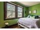 Bright bedroom features hardwood floors, natural light and vibrant green walls creating a cozy and inviting atmosphere at 741 Dequincy St, Indianapolis, IN 46201