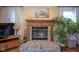 Living room with brick fireplace, wooden mantle and hearth, flanked by plants and open curtains at 7531 Bancaster Dr, Indianapolis, IN 46268