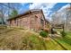 View of the brick house with deck from the sloped backyard, surrounded by trees at 8968 Old Haggard Rd, Morgantown, IN 46160