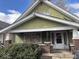 Olive green home exterior with covered porch and boarded window on a sunny day at 942 N Oxford St, Indianapolis, IN 46201