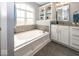 Bright bathroom featuring a soaking tub, white cabinetry, and ample natural light from the arched window at 10027 Landis Blvd, Fishers, IN 46040
