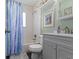 Updated bathroom with tile shower/tub, blue shower curtain and gray vanity with framed mirror at 10427 N Delaware St, Carmel, IN 46280