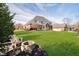 Expansive backyard with lush green lawn, a stone fire pit, and comfortable seating, perfect for relaxation and outdoor enjoyment at 14339 Jeremy Dr, Carmel, IN 46033