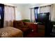 This bedroom features neutral tones, a flat-screen TV, a lounge chair and natural light from the window at 1508 N Woodridge Ave, Muncie, IN 47304