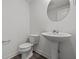 Stylish half-bath featuring a pedestal sink, modern toilet, round mirror and sleek fixtures at 3913 Highcrest Rd, Indianapolis, IN 46239