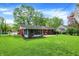 Large backyard featuring a well-maintained lawn, brick house, and sunroom addition at 4146 Roselawn Ave, Columbus, IN 47203