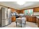 Sunlit kitchen showcasing stainless steel appliances, wood cabinets, and island table with eat-in space at 4146 Roselawn Ave, Columbus, IN 47203