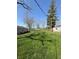 Expansive backyard with lush green grass, mature shade trees, and detached outbuildings at 4904 Betholm Dr, Indianapolis, IN 46239