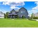 Beautiful home exterior featuring a well-manicured lawn, blue skies, and a unique roof design at 5120 Melbourne Pl, Zionsville, IN 46077