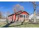 Side exterior view of red brick and wood home showing charming architectural details, yard, and mature trees at 5330 Manker St, Indianapolis, IN 46227
