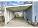 Open carport attached to a blue house, overlooking a grassy yard and outbuilding at 5350 E 20Th Pl, Indianapolis, IN 46218