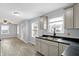 A bright kitchen features gray cabinets, dark countertops, wood floors and a view of the living area at 5350 E 20Th Pl, Indianapolis, IN 46218