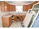 The kitchen features warm wood cabinetry, double basin sink, and great potential for improvements at 553 N Traub Ave, Indianapolis, IN 46222