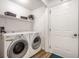 Well-lit laundry room with modern washer and dryer, shelving, and a door to the side yard at 5836 Andover Rd, Indianapolis, IN 46220