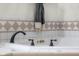 Close up of a soaking tub with decorative tile and bronze hardware at 6043 Acorn Dr, Columbus, IN 47201