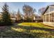 A spacious backyard featuring a well-maintained lawn and mature trees with an enclosed porch attached to the house at 7021 Warwick Rd, Indianapolis, IN 46220