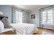 Serene bedroom featuring hardwood floors, two windows with patterned curtains, and soft blue walls at 7021 Warwick Rd, Indianapolis, IN 46220
