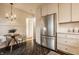 Well-lit kitchen features stainless steel refrigerator, stylish chandelier, sleek white cabinetry, and dark hardwood floors at 7021 Warwick Rd, Indianapolis, IN 46220