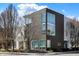 Street-level view of a modern townhome with a combination of dark brick and white siding, framed by bare trees against a blue sky at 932 Broadway St # 15, Indianapolis, IN 46202